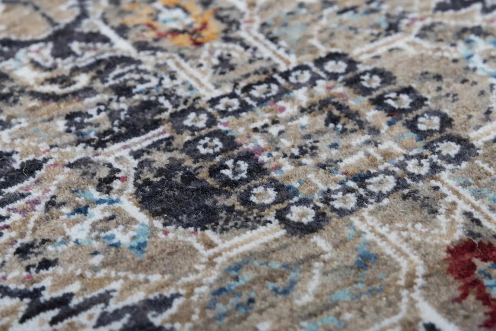 Vintage-style beige area rug with intricate patterns in blues, reds, and black, ideal for adding elegance to any room.
