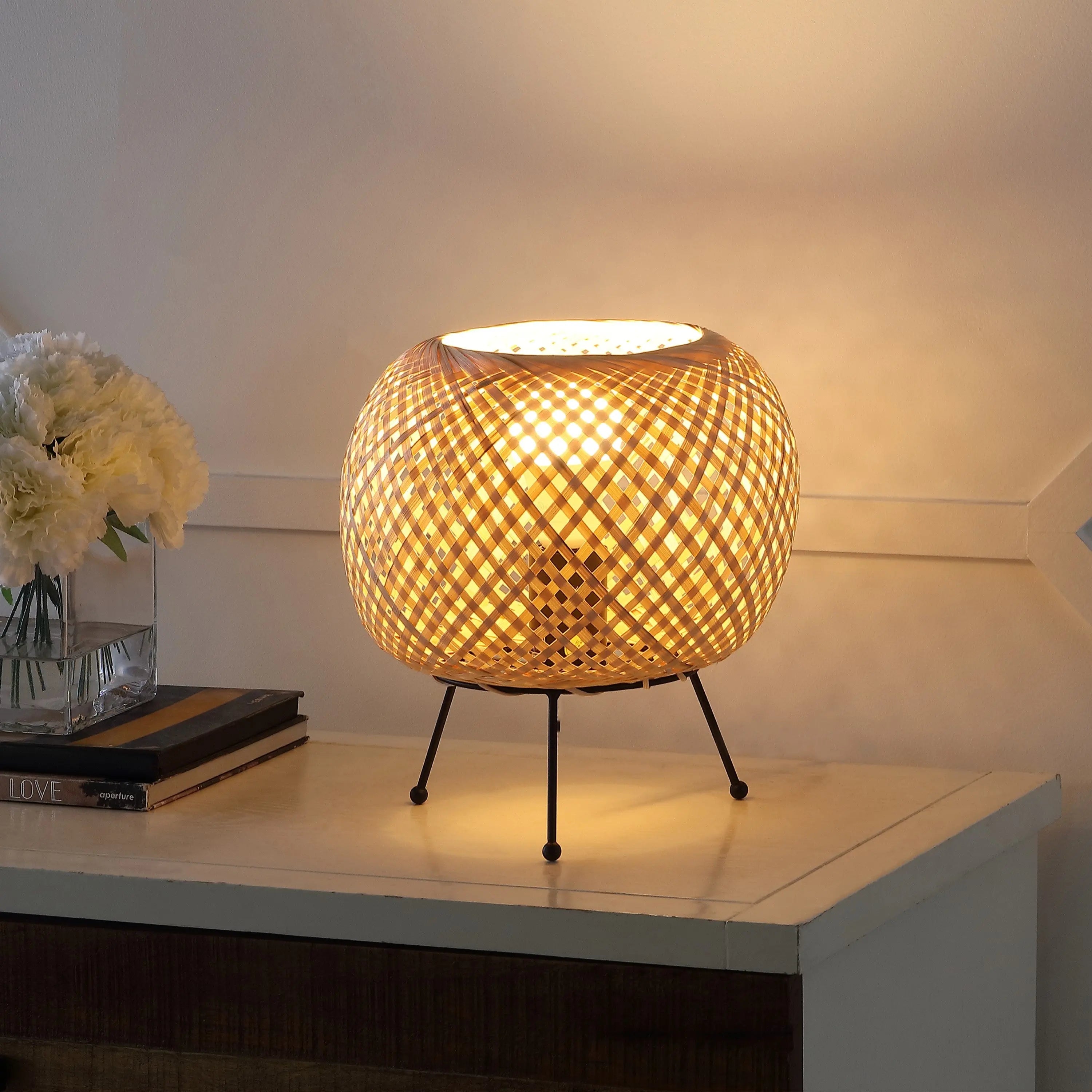 Woven rattan table lamp with a warm glow, featuring a black metal base and stylish, modern design. Perfect for ambient lighting.