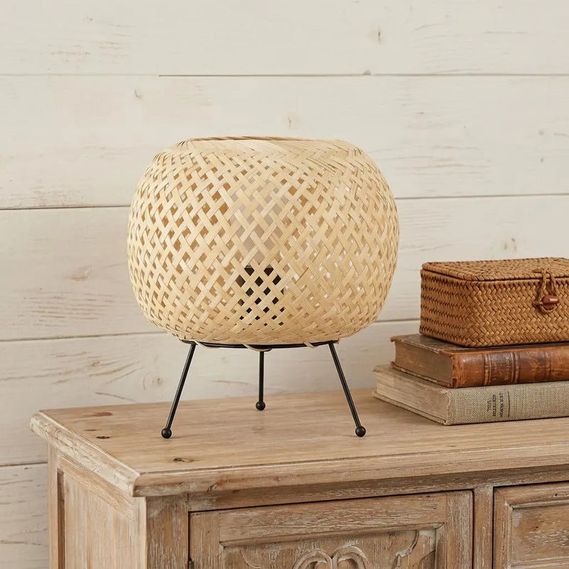 Natural woven rattan lamp with black metal legs, perfect for boho-style home decor.