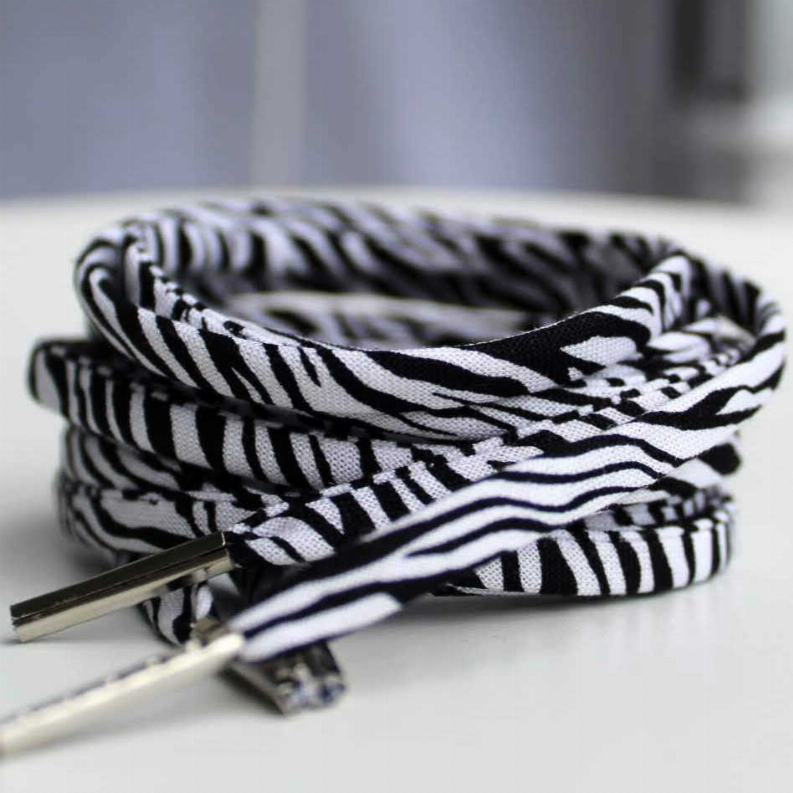 Zebra-print shoelaces with metal aglets, close-up coiled laces in black-and-white.