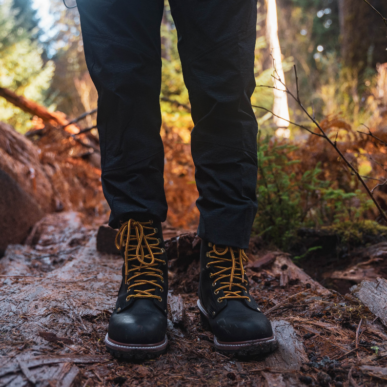 Waterproof steel toe logger boots worn with dark pants on rocky outdoor ground