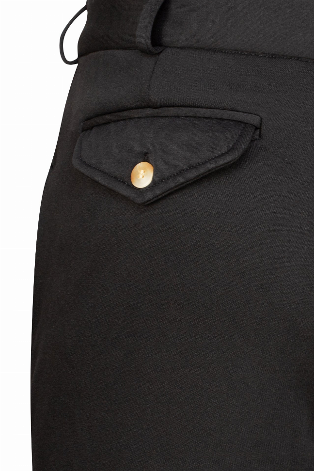 Men's black unifleece breeches close-up, curved pocket opening with gold-tone button