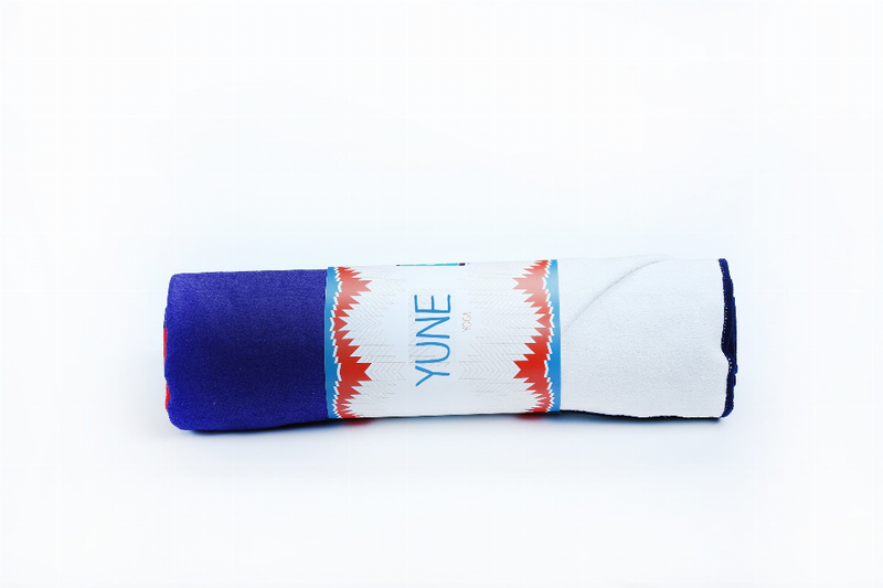 Rolled yoga towel with dark blue end and white band featuring red zigzag pattern