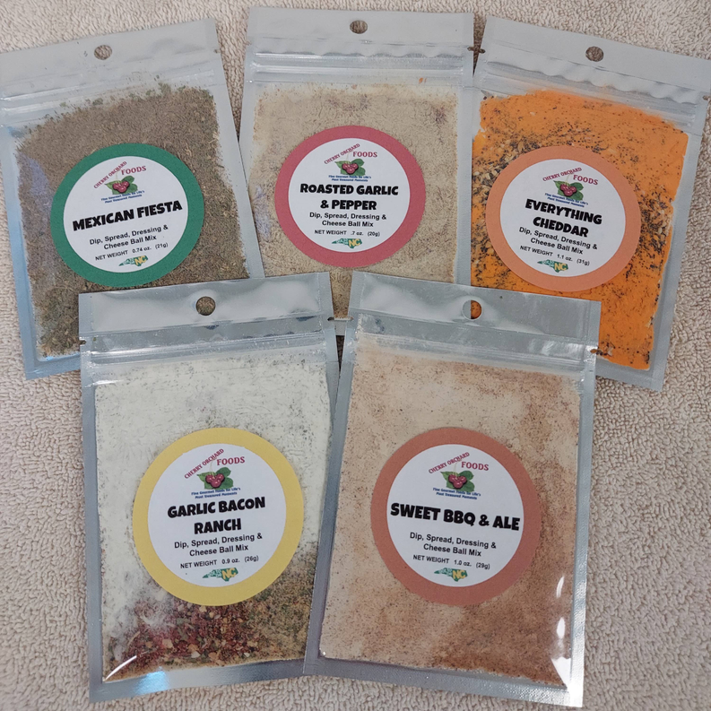 Set of dip mix packets with labels: Mexican Fiesta, Roasted Garlic & Pepper, Everything Cheddar, Garlic Bacon Ranch, Sweet BBQ & Ale