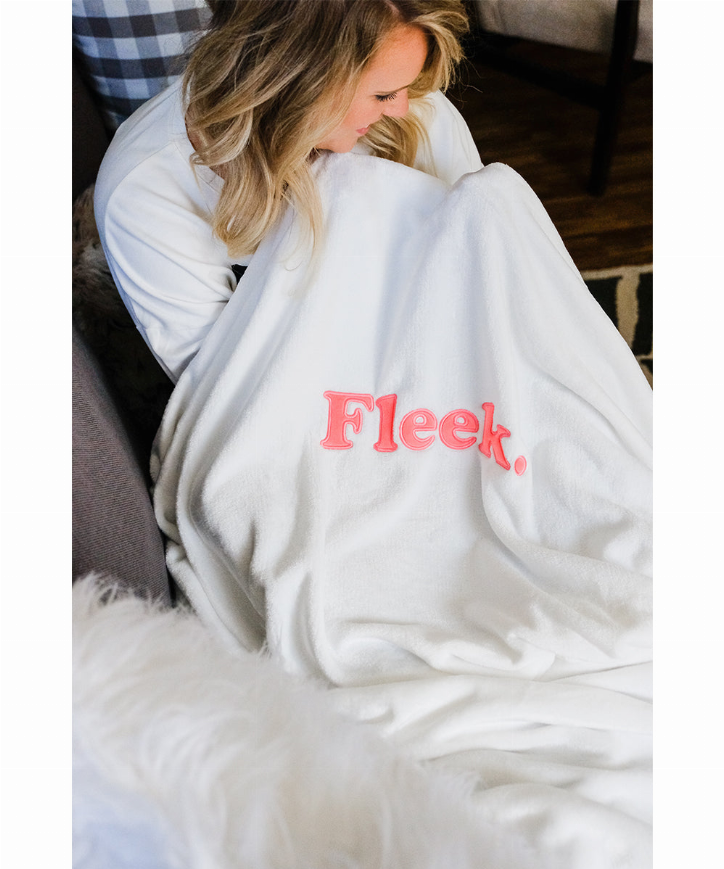 Plush fleece nap blanket draped over shoulders, white with Fleek logo