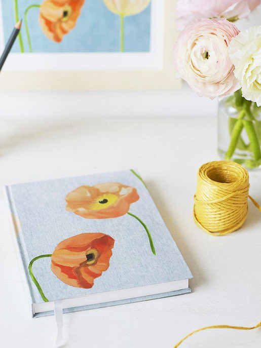 Light blue journal with illustrated orange flowers and green stems on the cover