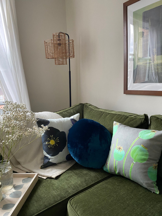 Rectangular throw pillow with green seed-pod print on gray fabric, on sofa