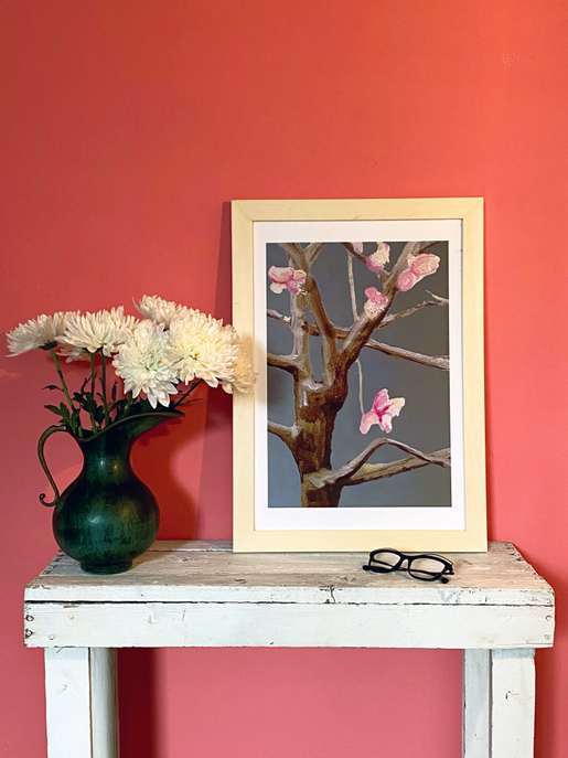 Framed art print of a tree branch with pink flowers on dark grey