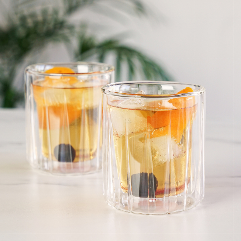 Double-walled rocks glasses in clear glass with amber drink and ice, set of 2