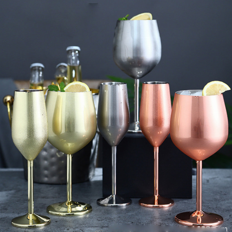 Set of metallic stem cocktail glasses in gold, silver, and rose tones with lemon garnish