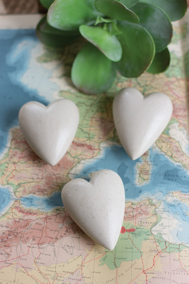 Set of six hand-carved stone hearts, off-white, three hearts shown on a map