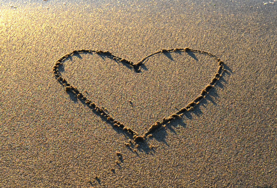 Heart-shaped sand magnet accessory with dotted dark outline on sand surface