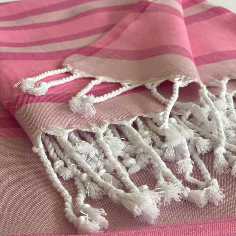 Pink striped Turkish towel close-up with thick white braided tassel fringe