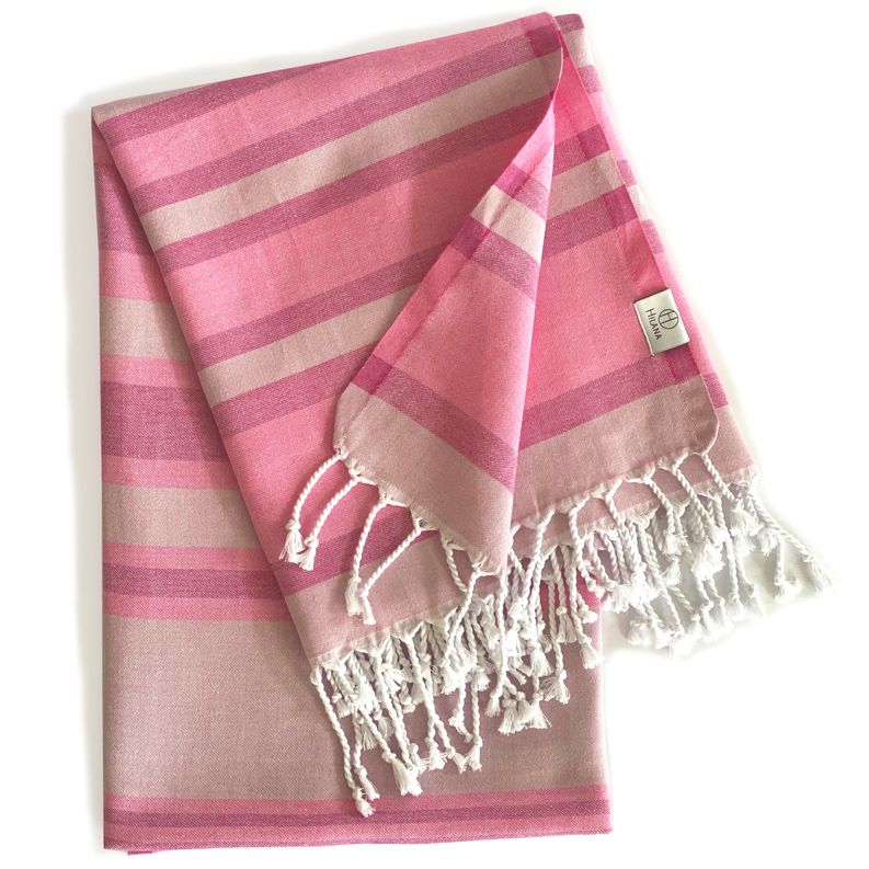 Pink Turkish towel folded with wide stripe pattern and white fringed ends