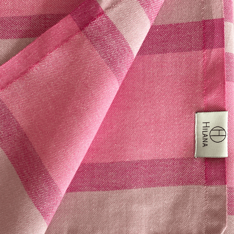 Pink-and-rose striped Turkish towel with woven texture and corner label
