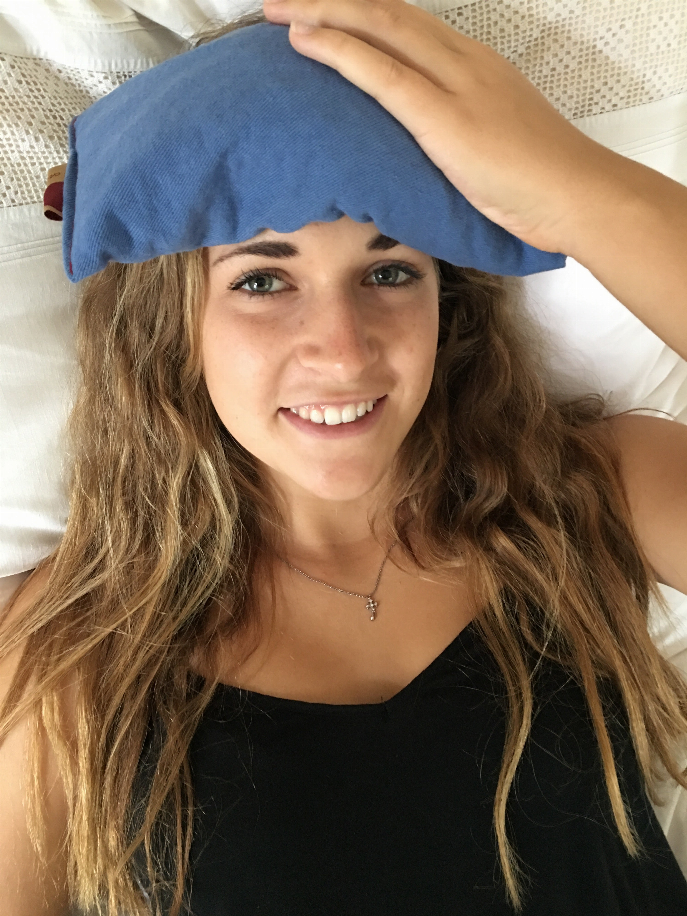 Blue denim eye pillow held over forehead with soft wave edges