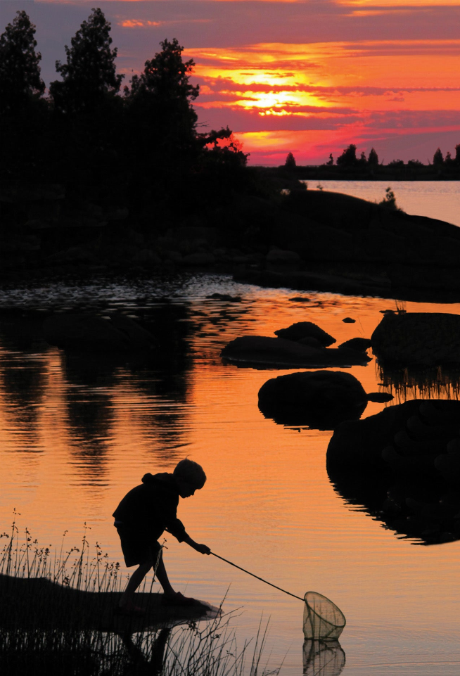 Motion postcard showing a person fishing by a calm lake at sunset with rocks