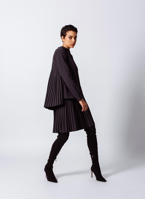 Black pleated midi skirt with accordion pleats and elastic waistband, walking full-body