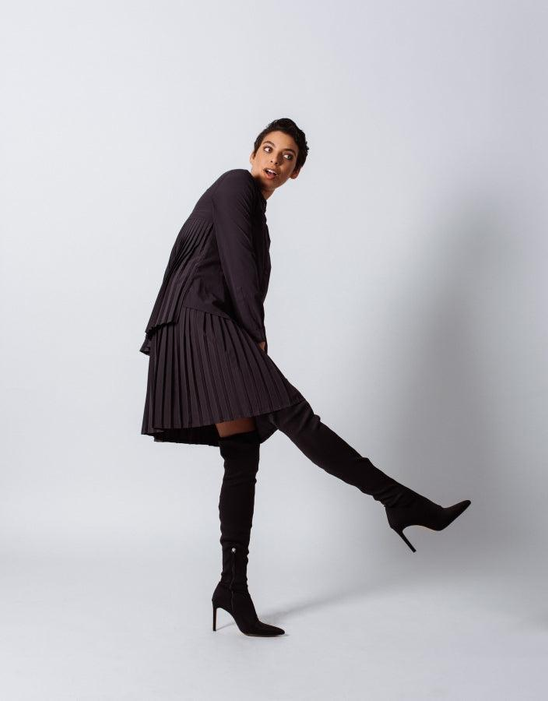 Black pleated midi skirt with accordion pleats and elastic waistband, standing profile