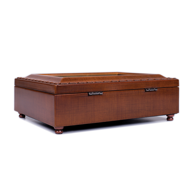 Wooden music box with hinged lid and decorative base feet, angled side view