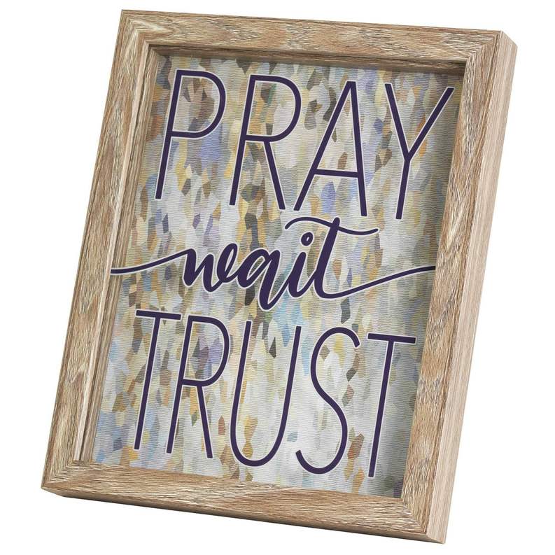 Wall art in light wood frame with 'PRAY wait TRUST' text and abstract pattern