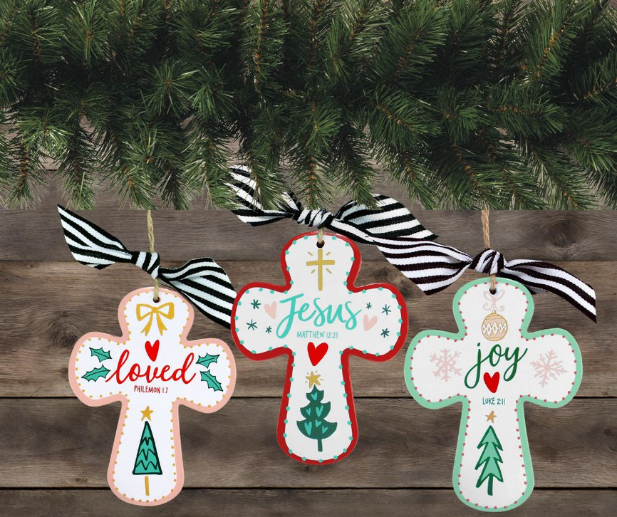 Three Jesus cross Christmas ornaments with striped bows on wooden background