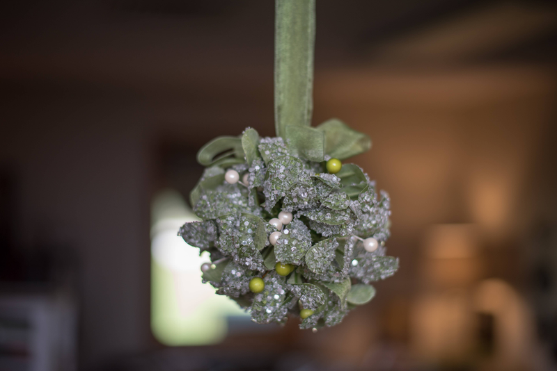 Kissing ball ornament close-up with green glitter leaves, pearls, and ribbon ties