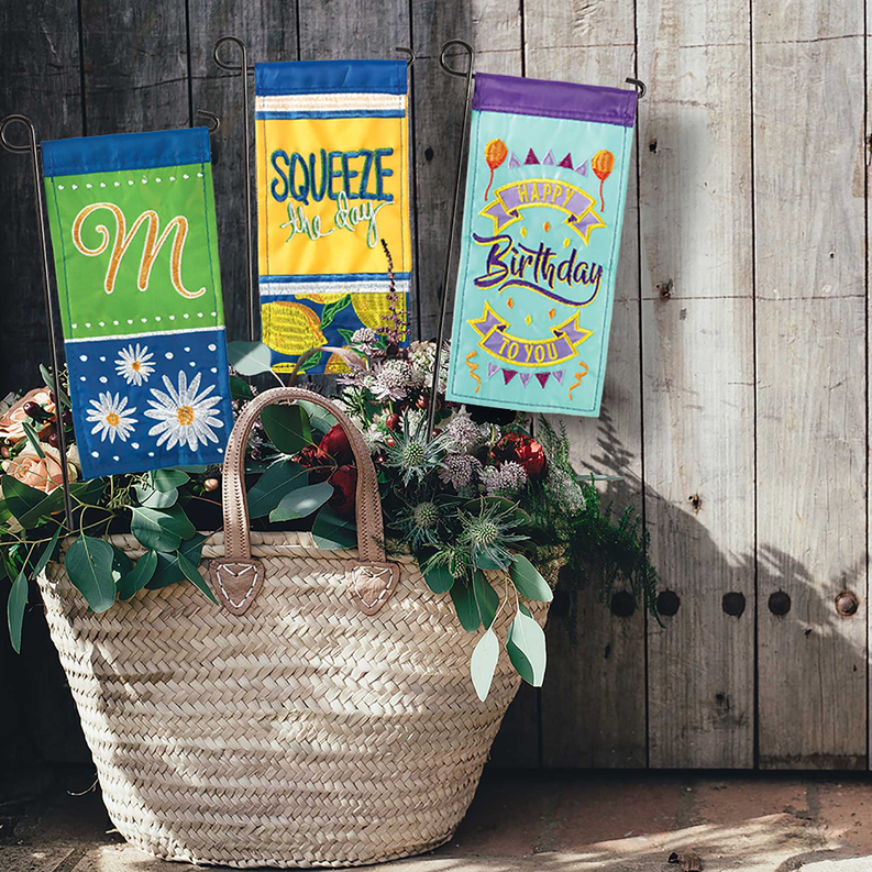 Set of mini garden flags with colorful panels and monogram designs on hooks