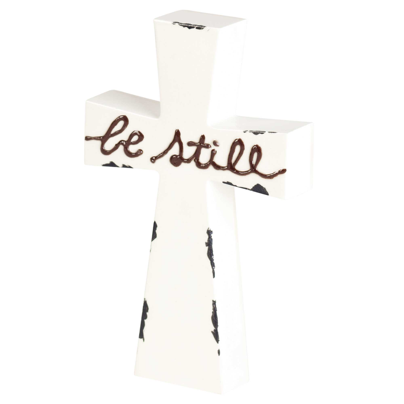 White tabletop cross with "be still" script enamel-look lettering
