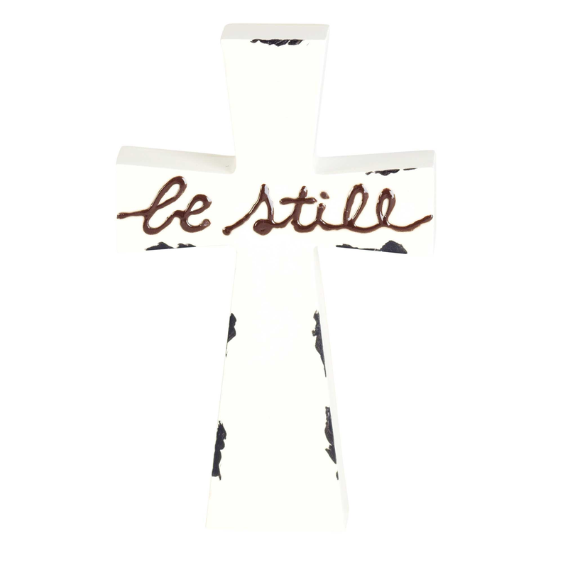 Front-facing white tabletop cross with "be still" script and dark accent marks