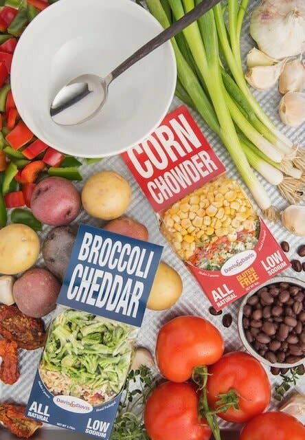 Broccoli cheddar mix pouches with blue labels among vegetables and beans
