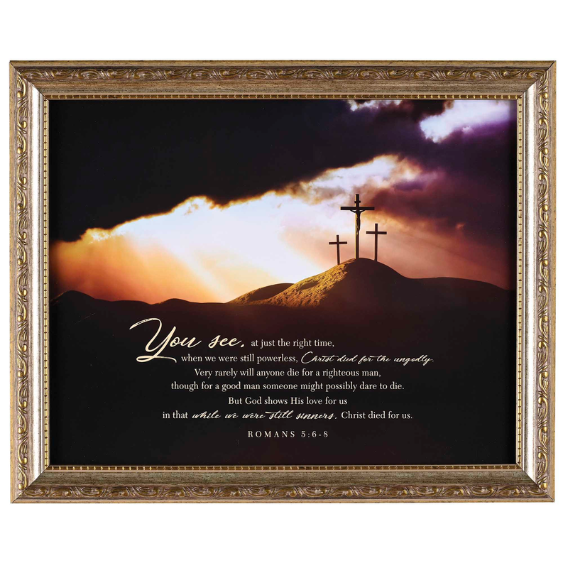 Framed Christian wall art with ornate gold frame, mountain cross scene and Romans 5:6-8 text