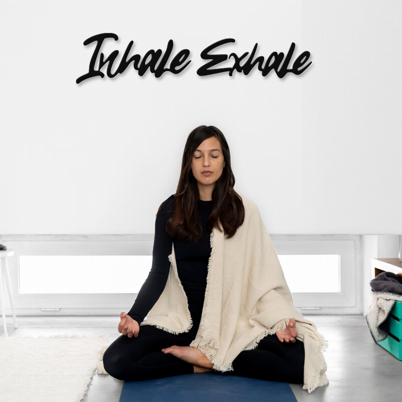 Metal wall art with black script text reading “Inhale Exhale”.