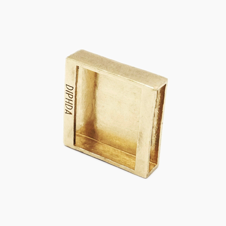 Gold moon charm back with an engraved mark inside the square frame