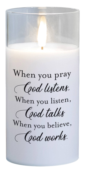LED candle with clear glass body, white wax, and religious quote text on front.