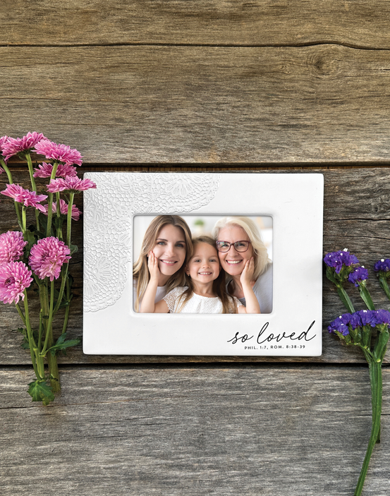 White lace-textured photo frame with window and three people, on wood with flowers