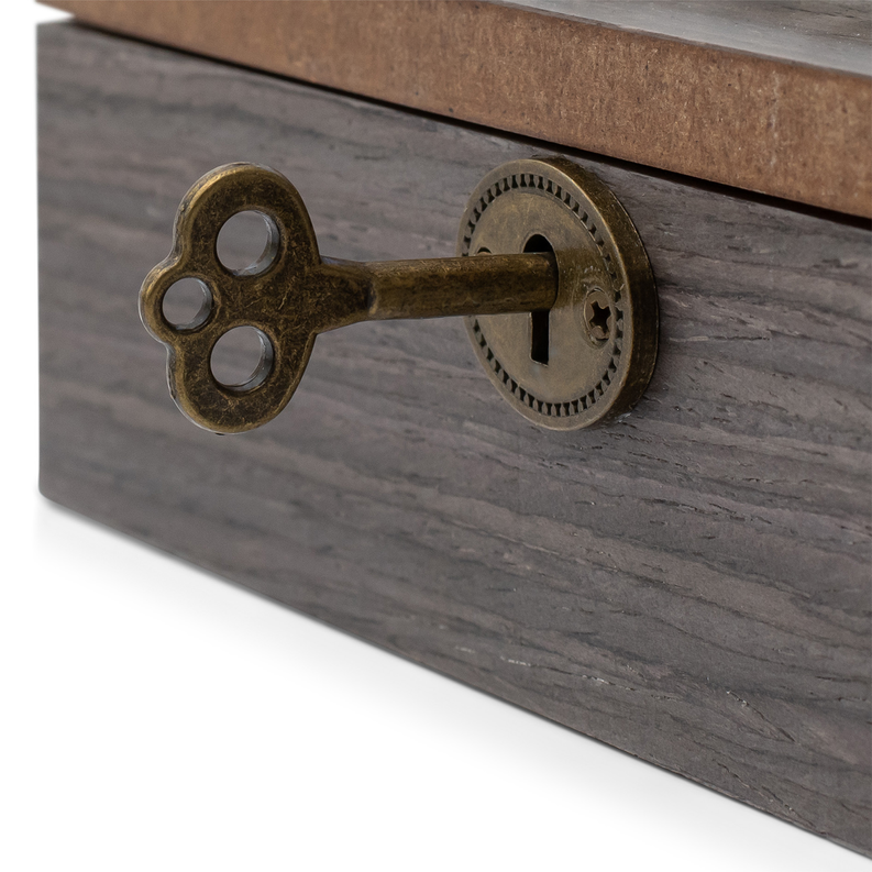 Close-up of brass key and latch hardware on dark wooden music box lid.
