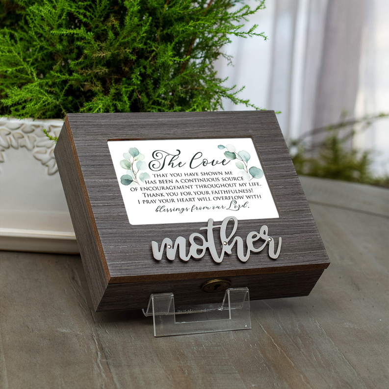 Wooden music box on display with floral message card and “mother” lettering.