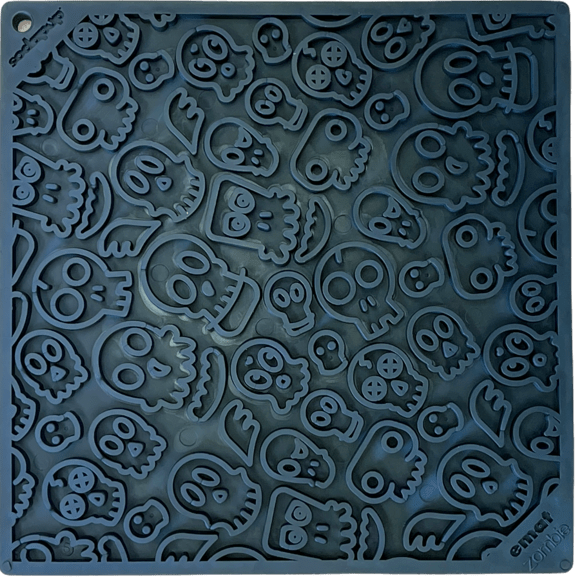 Close-up of dark rubber lick mat with raised zombie face and bone shapes