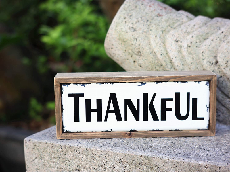 Tabletop wood block sign with 'THANKFUL' black lettering on white panel, on stone