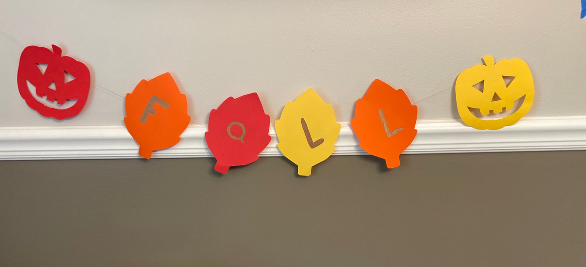 Paper cut-out banners with jack-o’-lantern and bat shapes in red, orange, and yellow