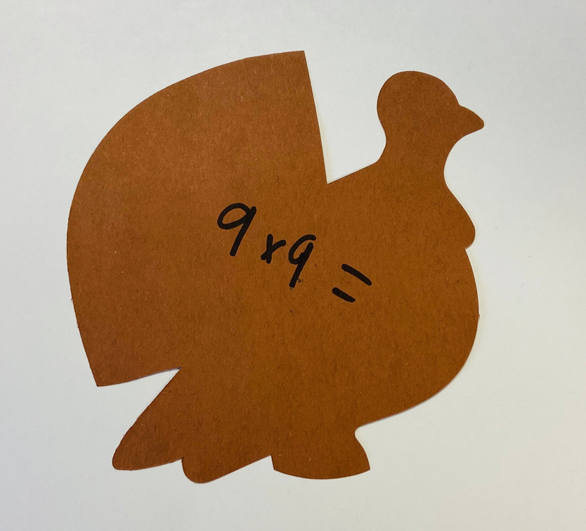 Brown paper cut-out chicken with “9xg” marking and stitched smile line detail