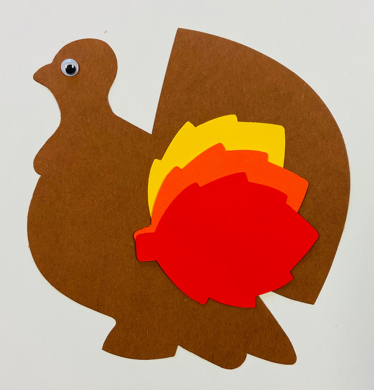 Brown turkey cut-out with layered red, yellow, and orange food-style shapes and eye dot