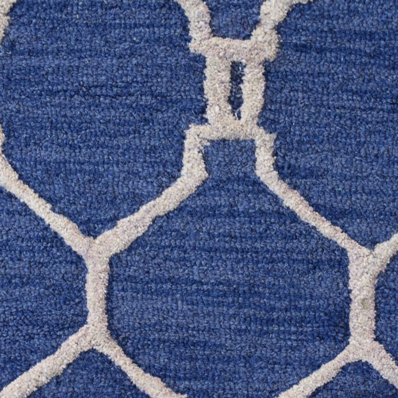 Blue wool runner rug close-up with white-outlined quatrefoil geometric pattern.