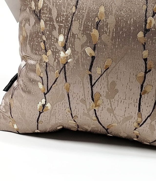 Taupe throw pillow cover with brass-gold branch design, close-up view of pattern and weave.
