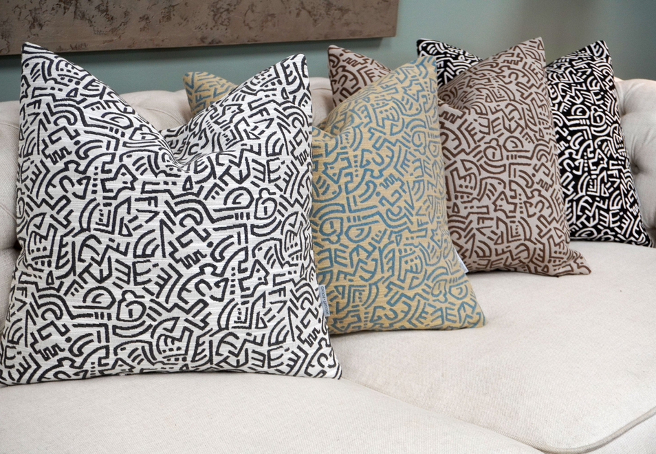 Pop Energy patterned throw pillows in white, blue, tan, and black