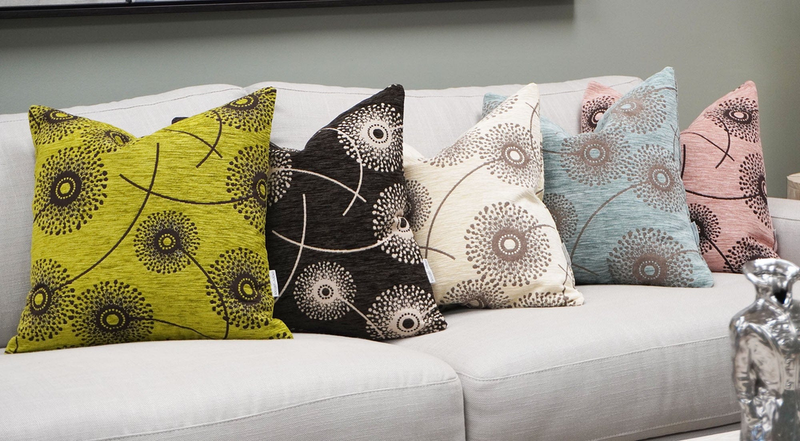 Patterned throw pillows on a sofa with green, black, cream, and blue designs.