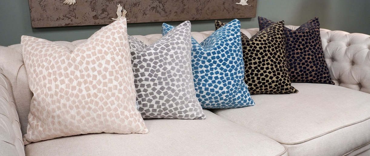 Geometric patterned throw pillows in light blue and beige on a white sofa