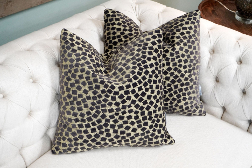 Geometric patterned throw pillows in beige and dark tones on a white sofa