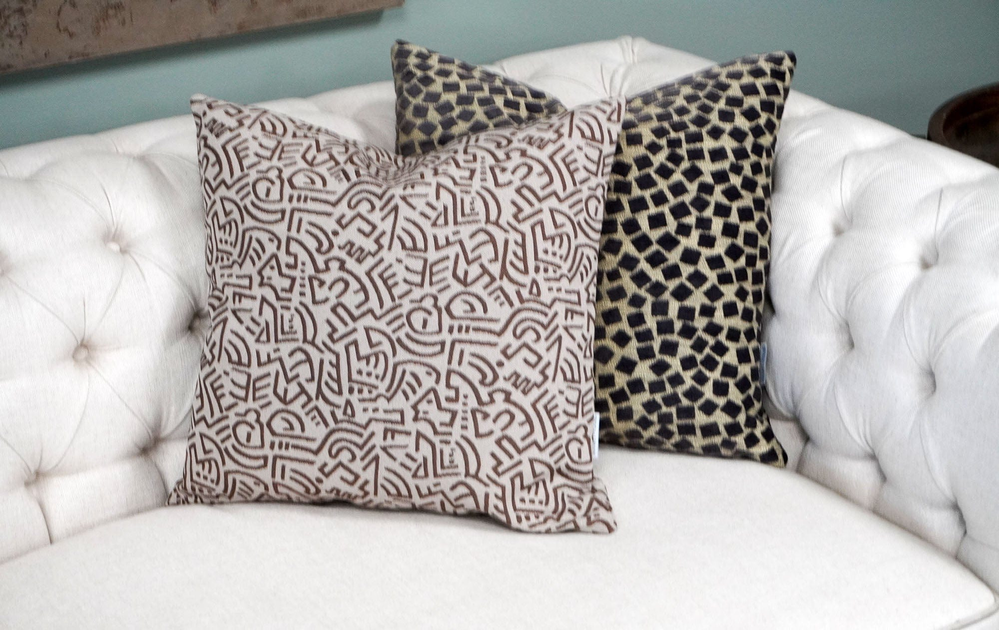 Two decorative throw pillows with geometric patterns in beige and dark tones